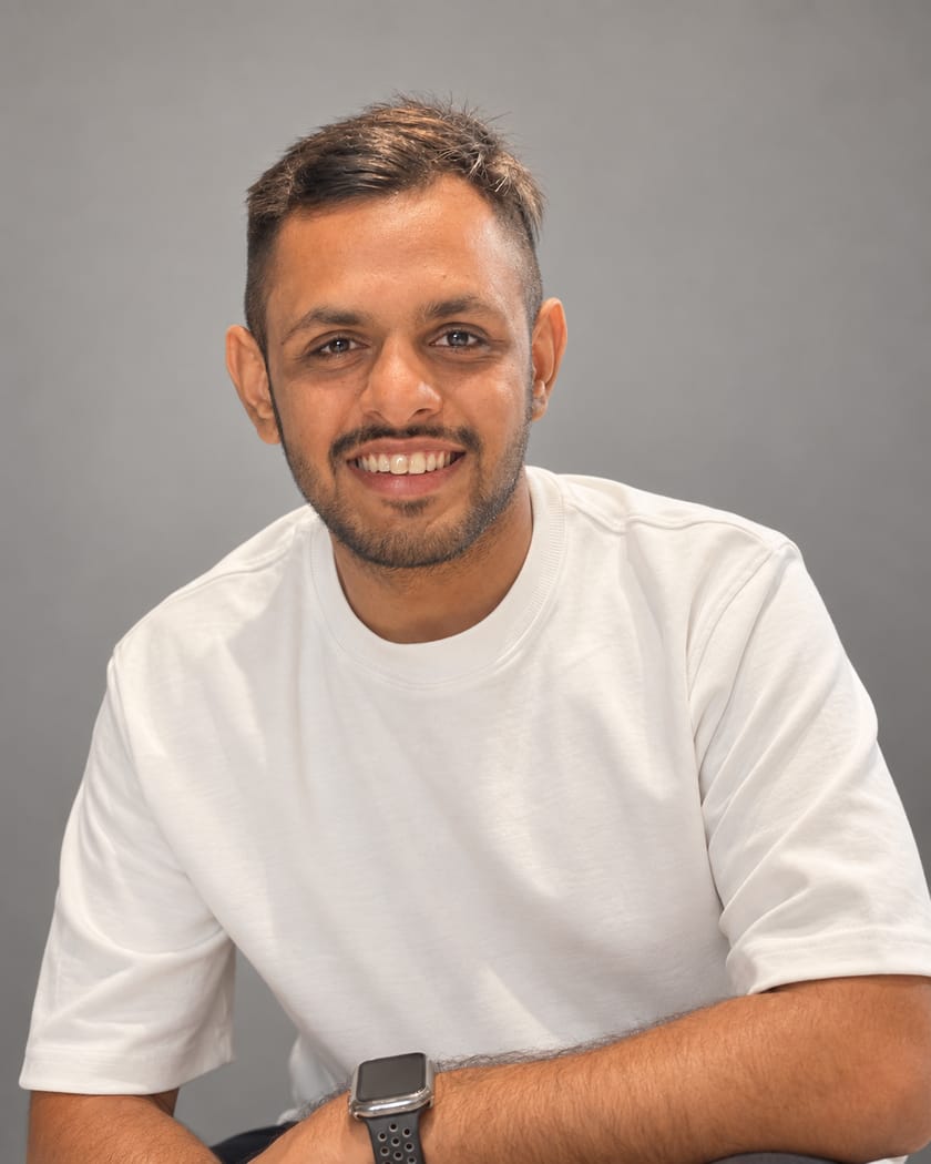 Kunj Patel, founder of Optiflow, smiling, in a white T-shirt against a grey background.